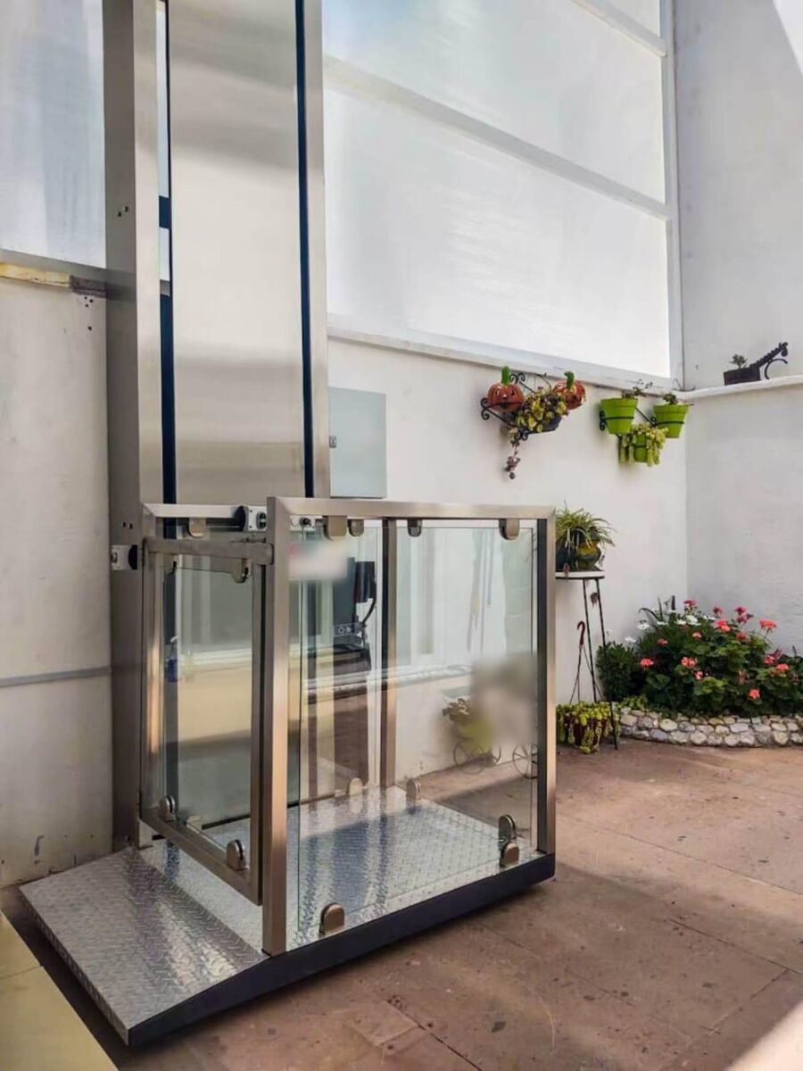 Stainless steel and glass platform lift in a courtyard